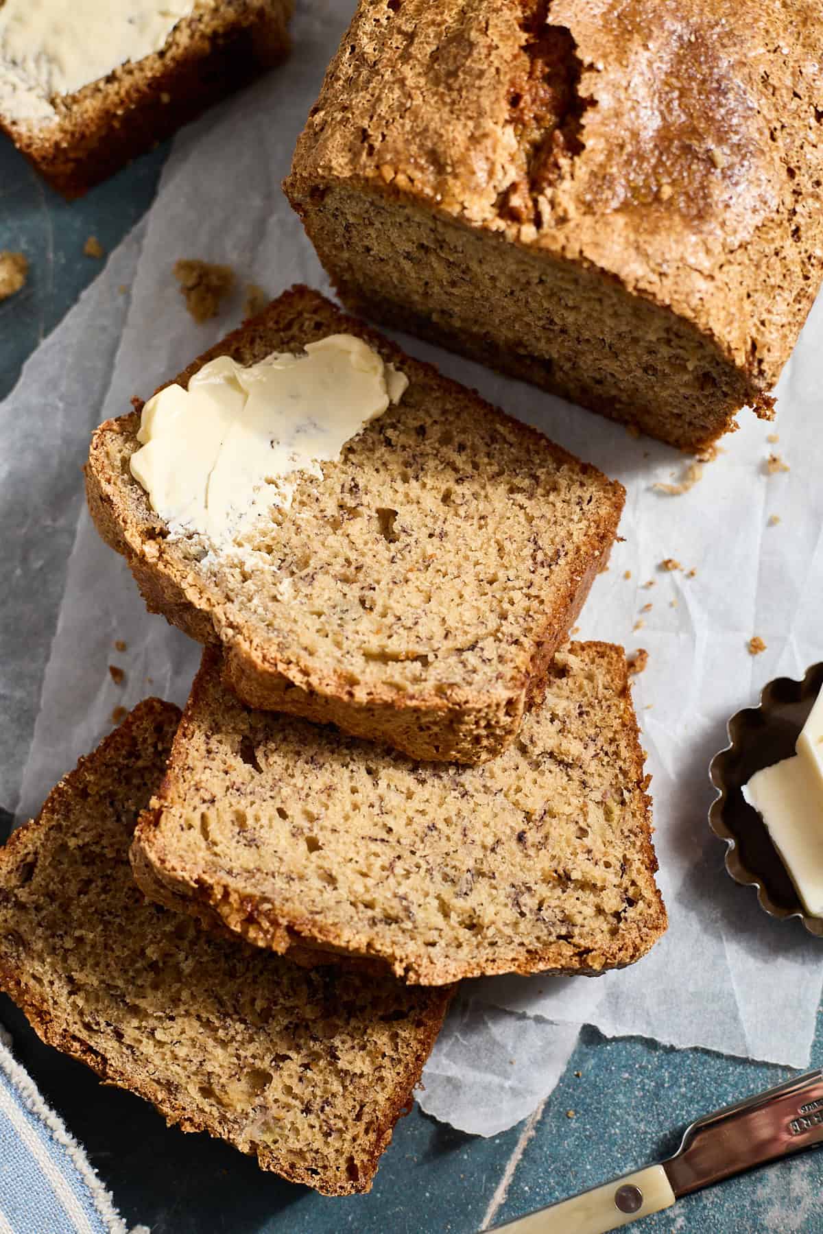 A sliced loaf of Sourdough Discard Banana Bread with a spread of butter.