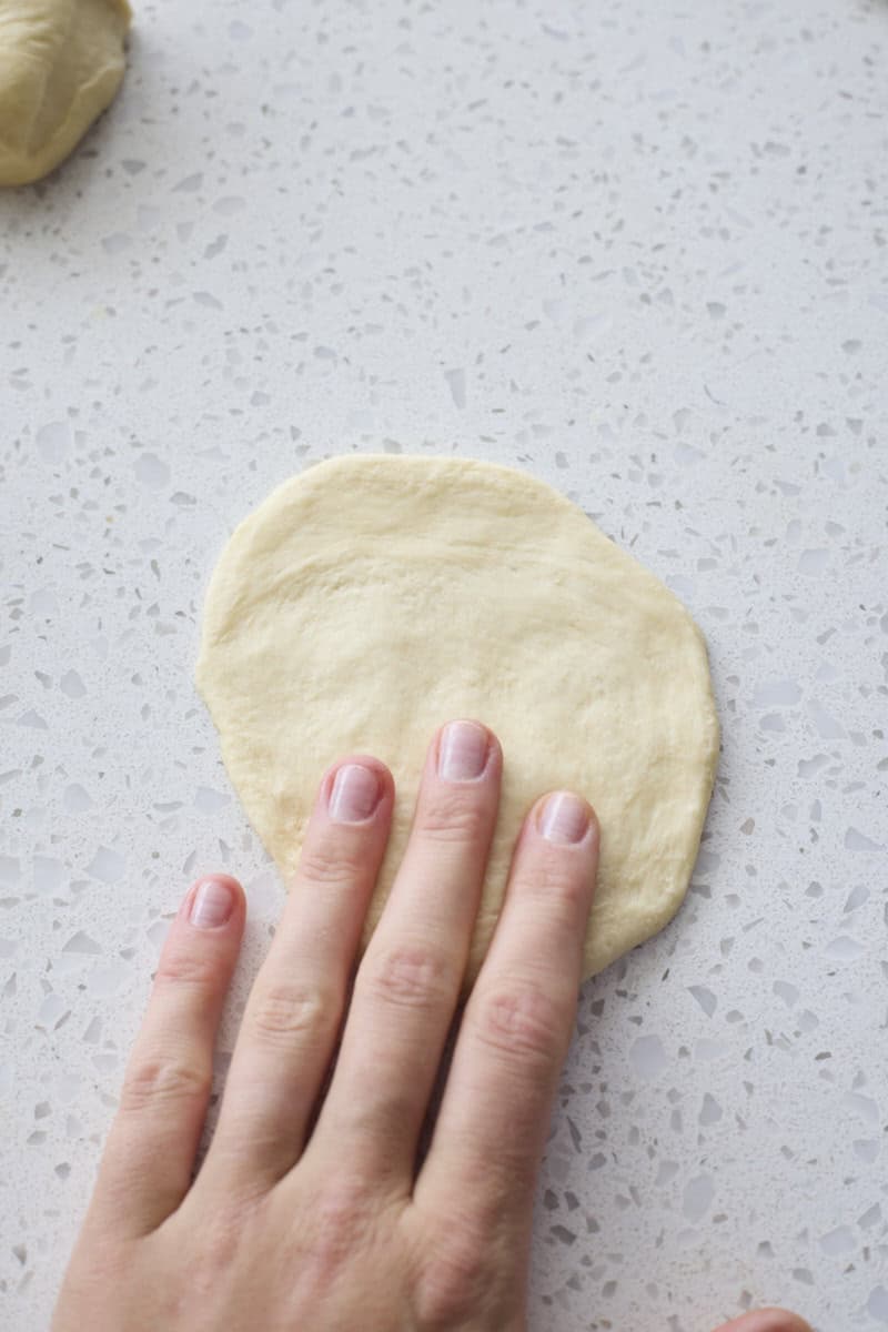 Dough piece flattened by hand.