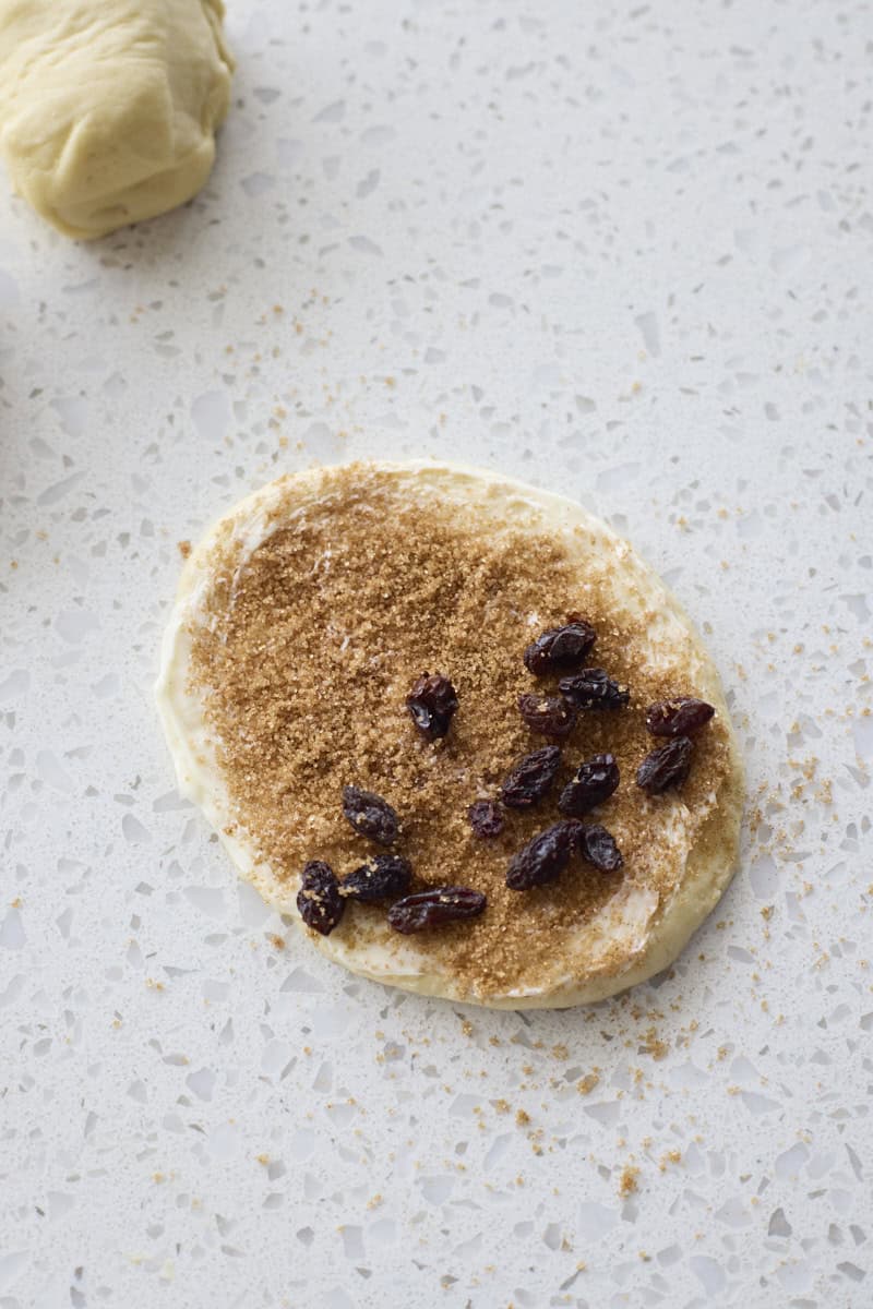 Dough piece sprinkled with cinnamon sugar and raisins.