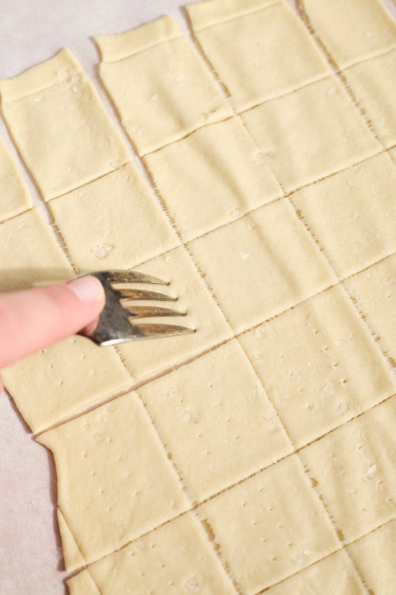 A fork poking holes in the Sourdough Discard Crackers.