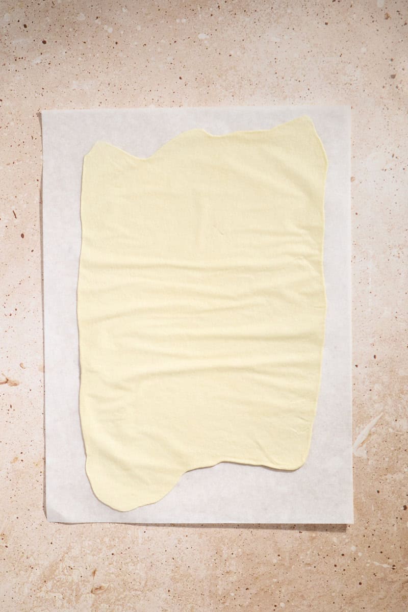 Dough rolled thin on a piece of parchment paper.