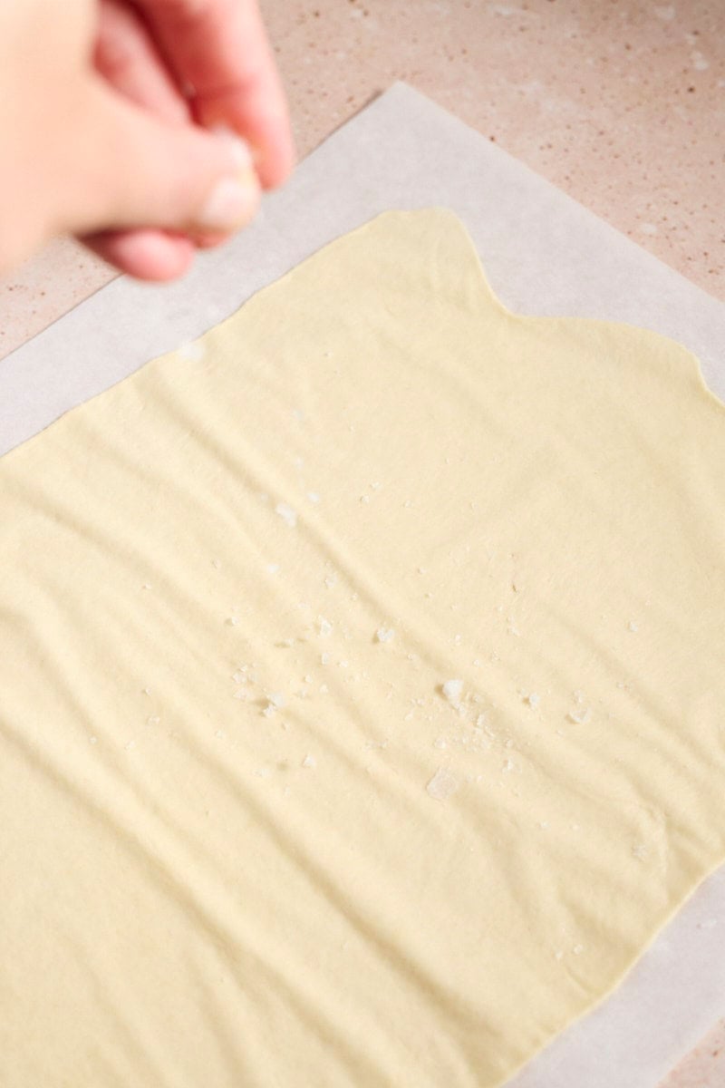 Sprinkling salt on the cracker dough.