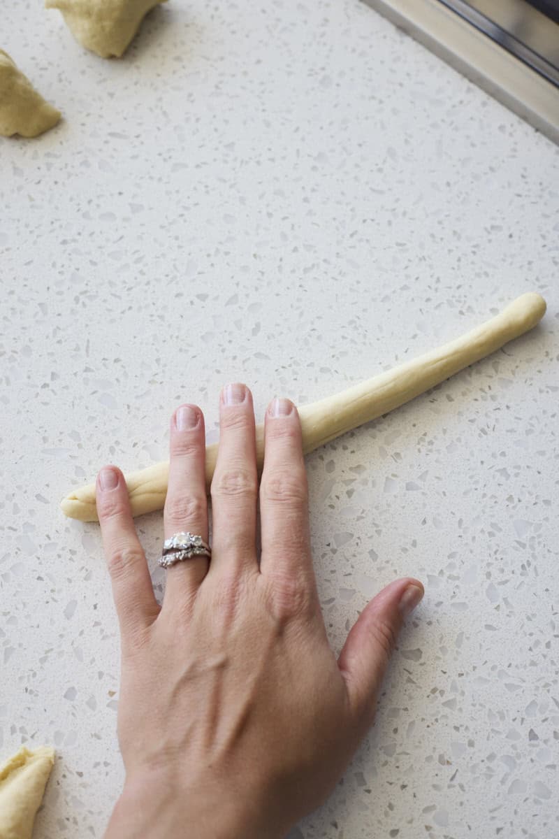 A hand rolling the dough into a rope.