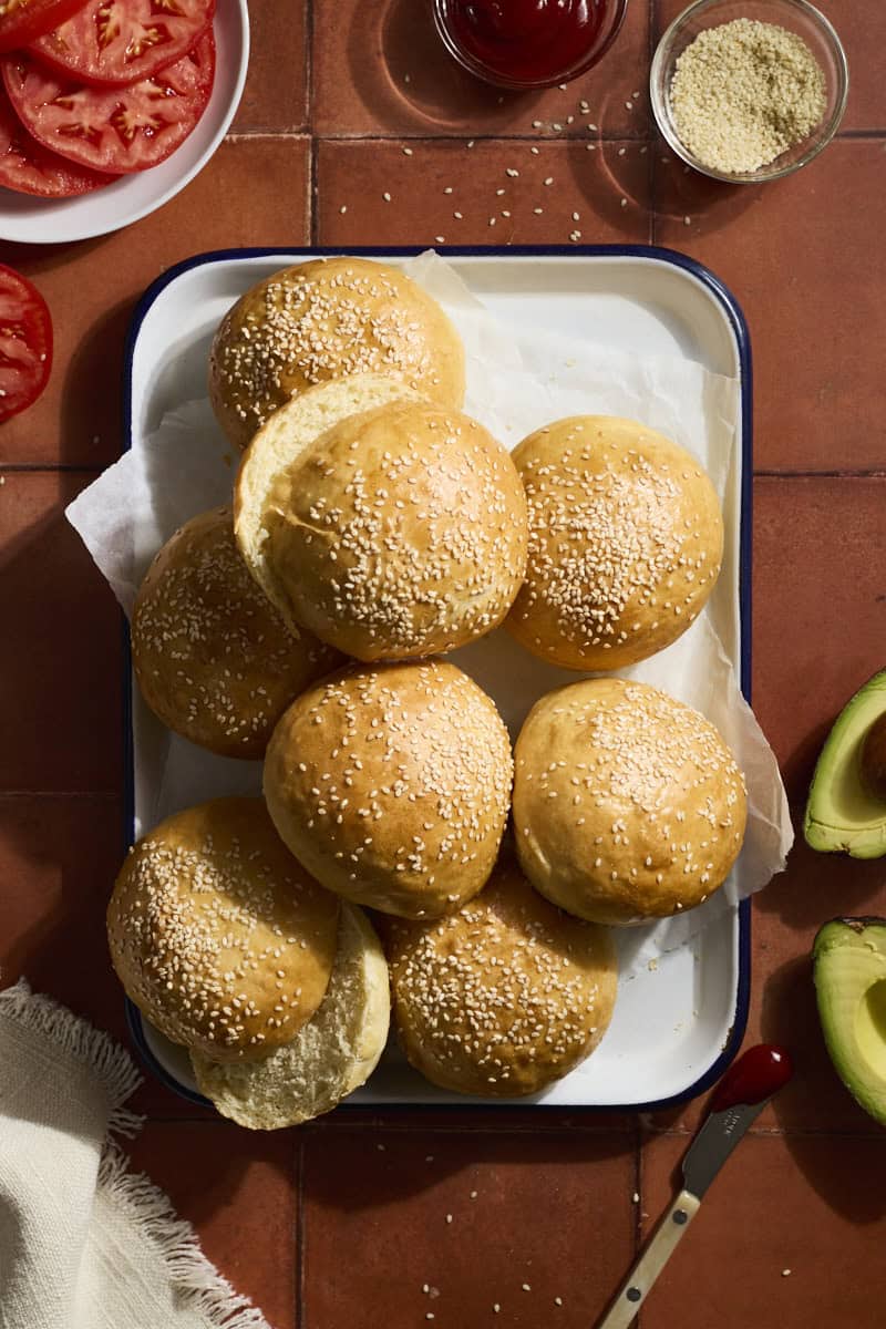 A stack of Sourdough Discard Hamburger Buns on a white tray.