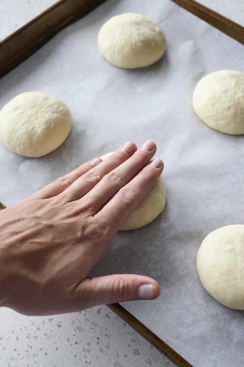 A hand pressing the buns into disks.