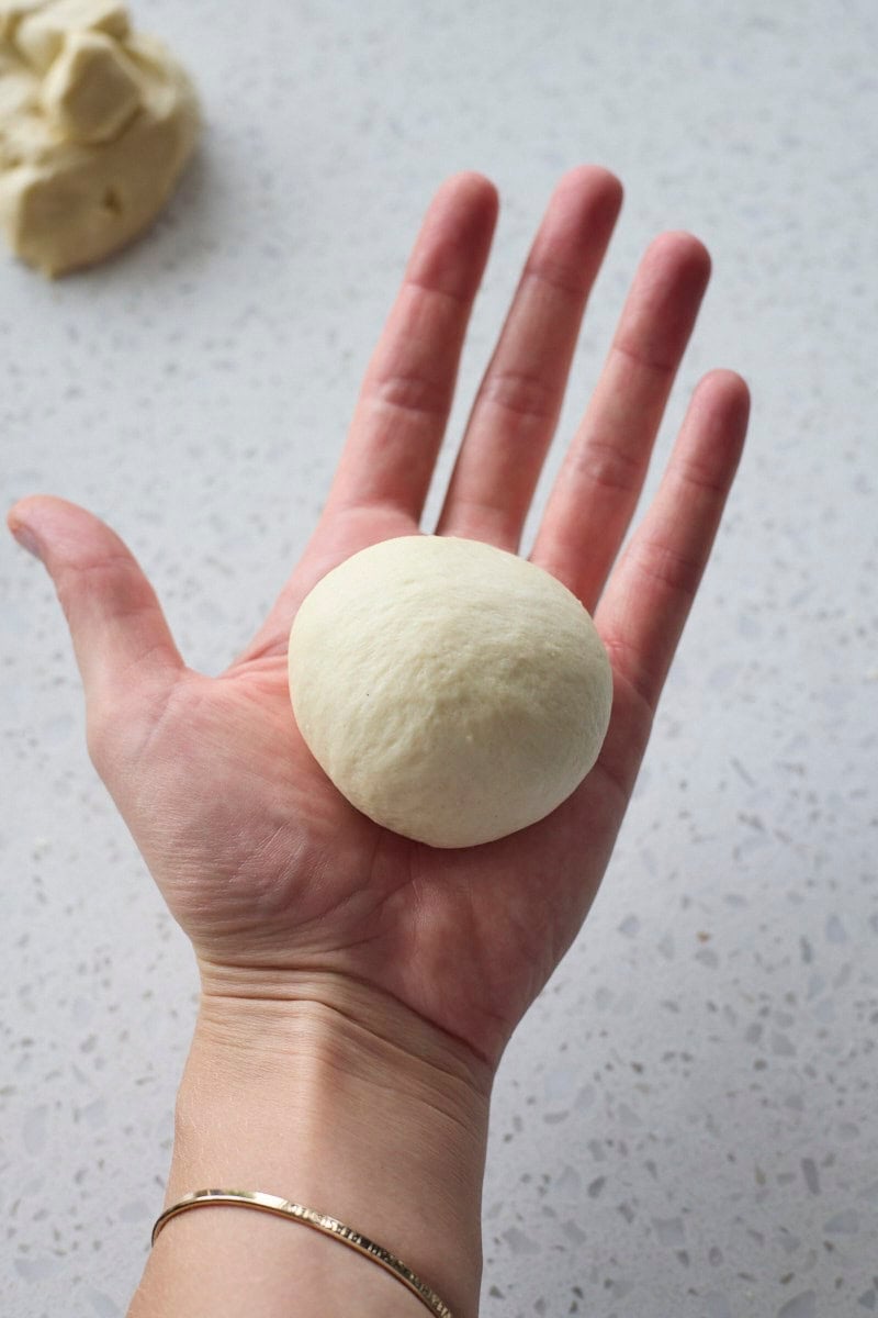 Dough rolled into a ball in the palm of a hand.