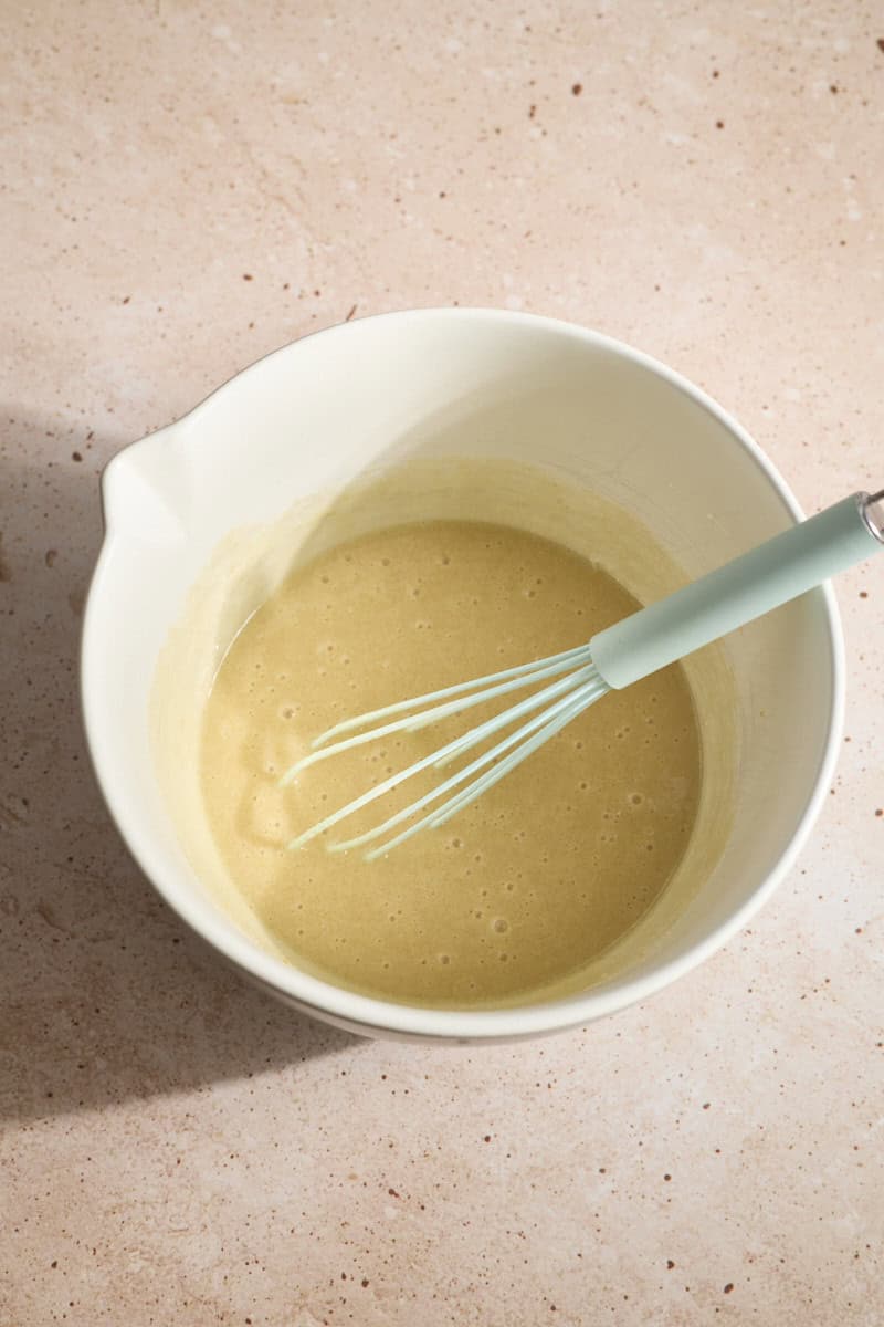 Wet ingredients and sugars mixed in a white bowl.