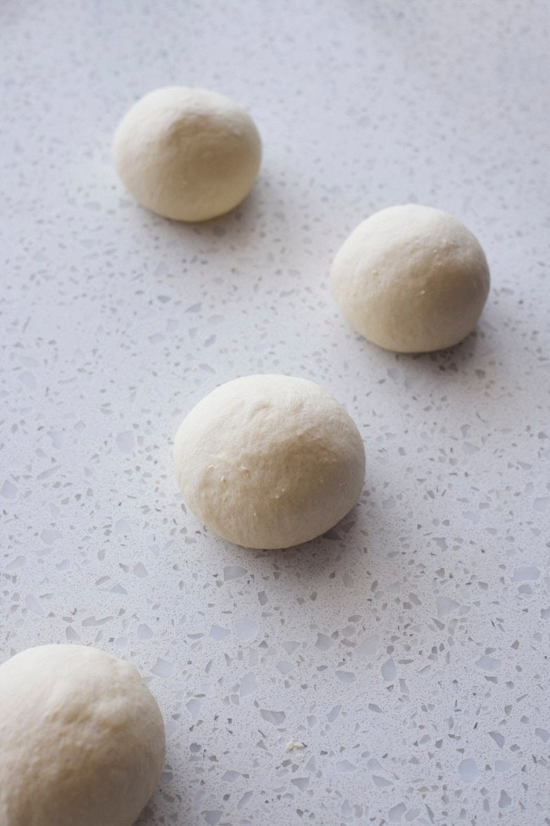 Dough shaped into balls on a work surface.