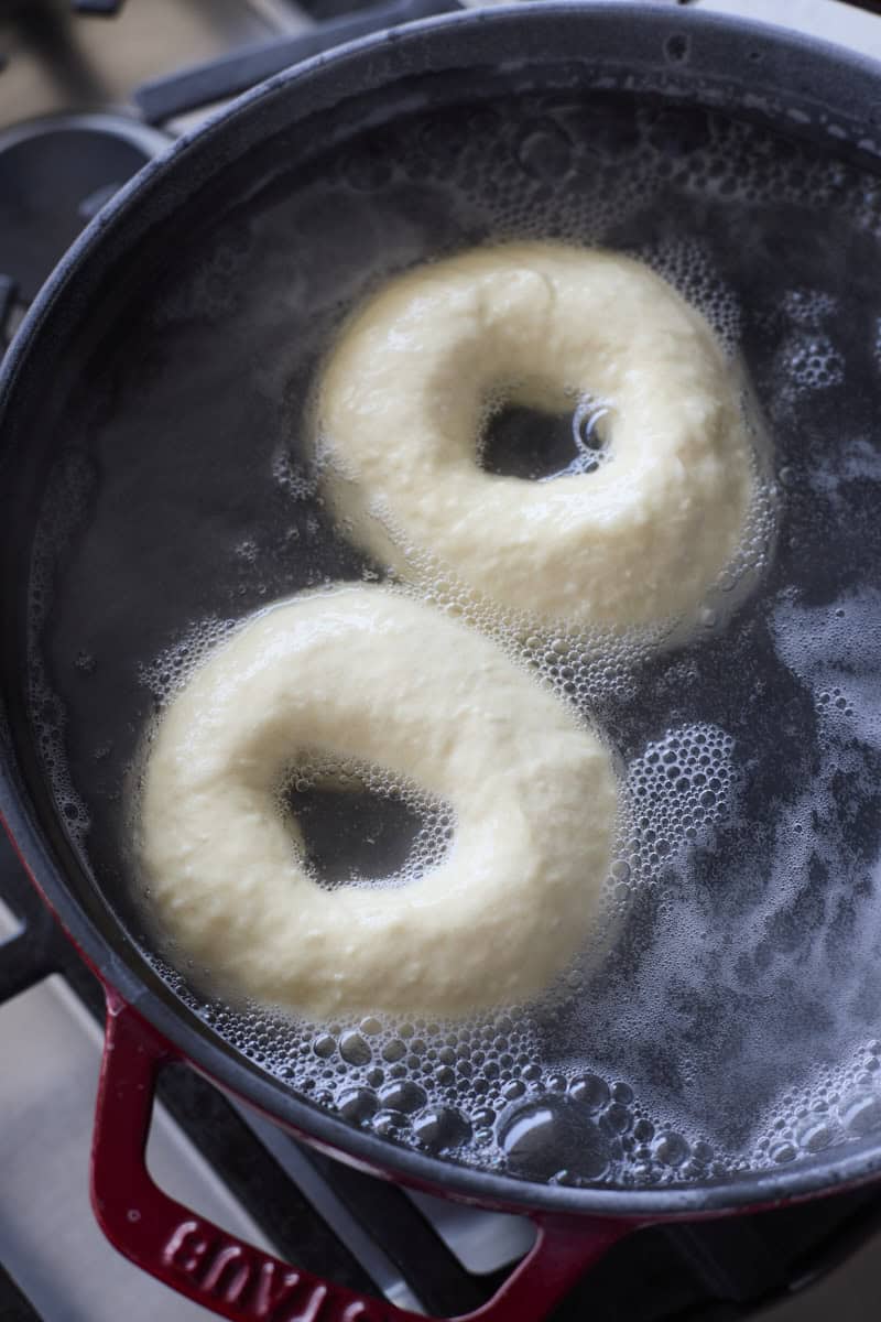 Bagels boiling in a pot of water.