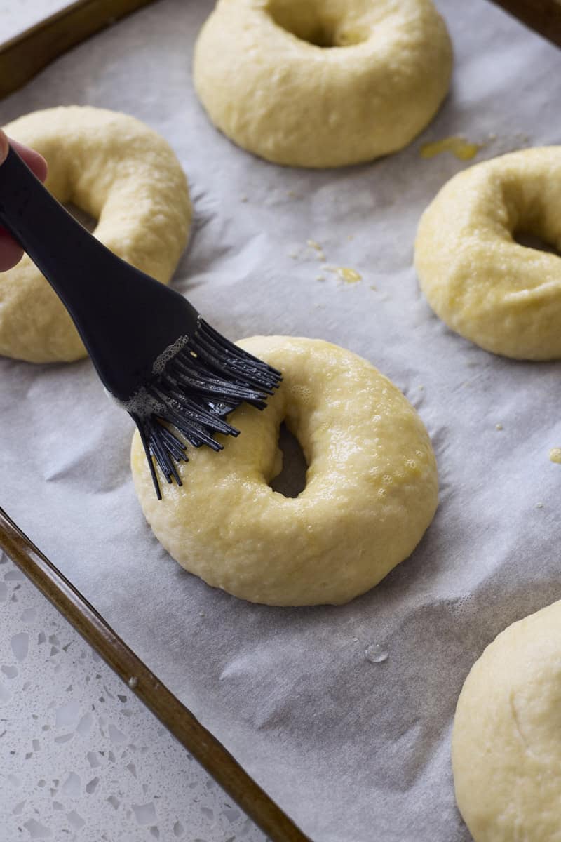 Brushing egg wash on a bagel.