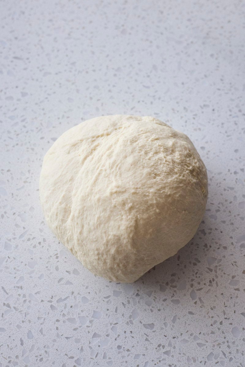 Kneaded dough in a ball on a work surface.