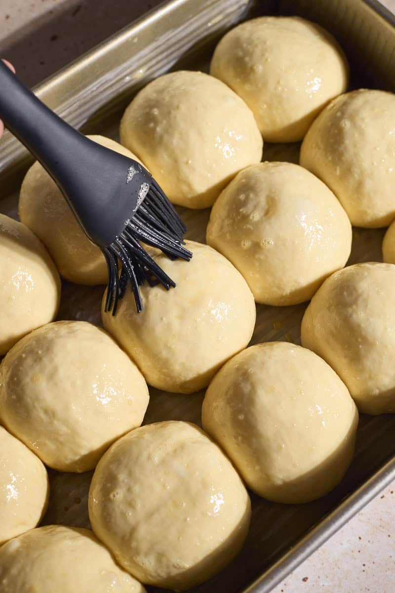 Rolls being brushed with egg wash before baking.