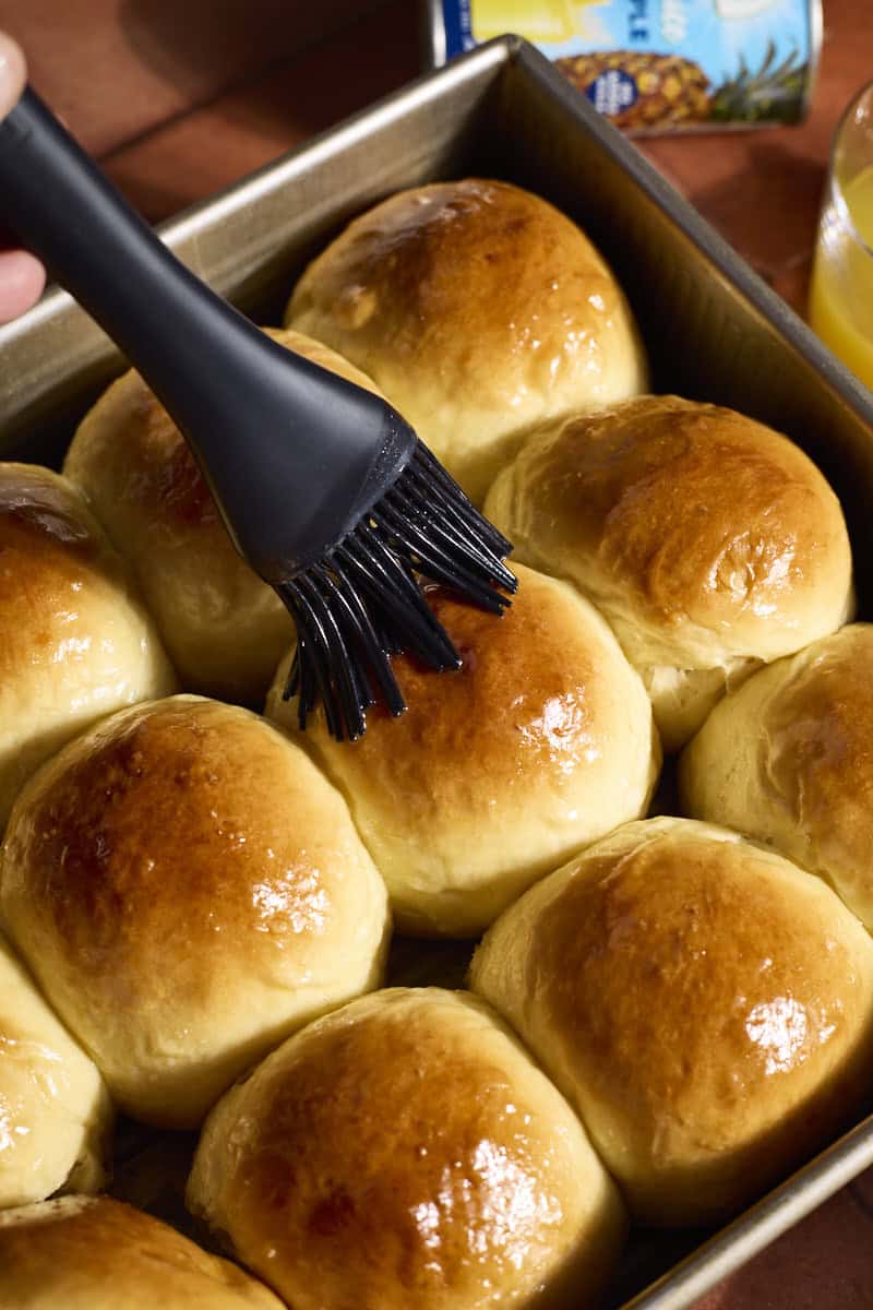 Rolls being brushed with melted butter.