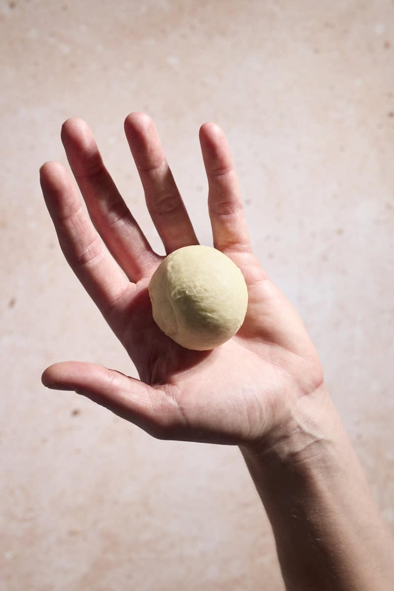 Dough shaped into a ball in a palm.
