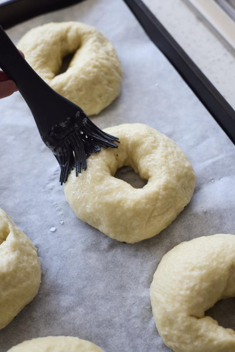 Bagels being brushed with egg wash.