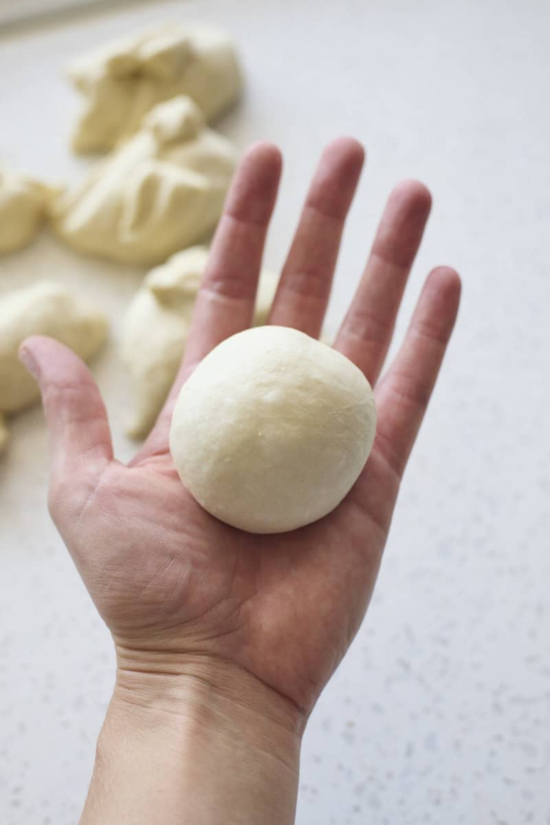 Dough shaped into a ball in the palm of hand.