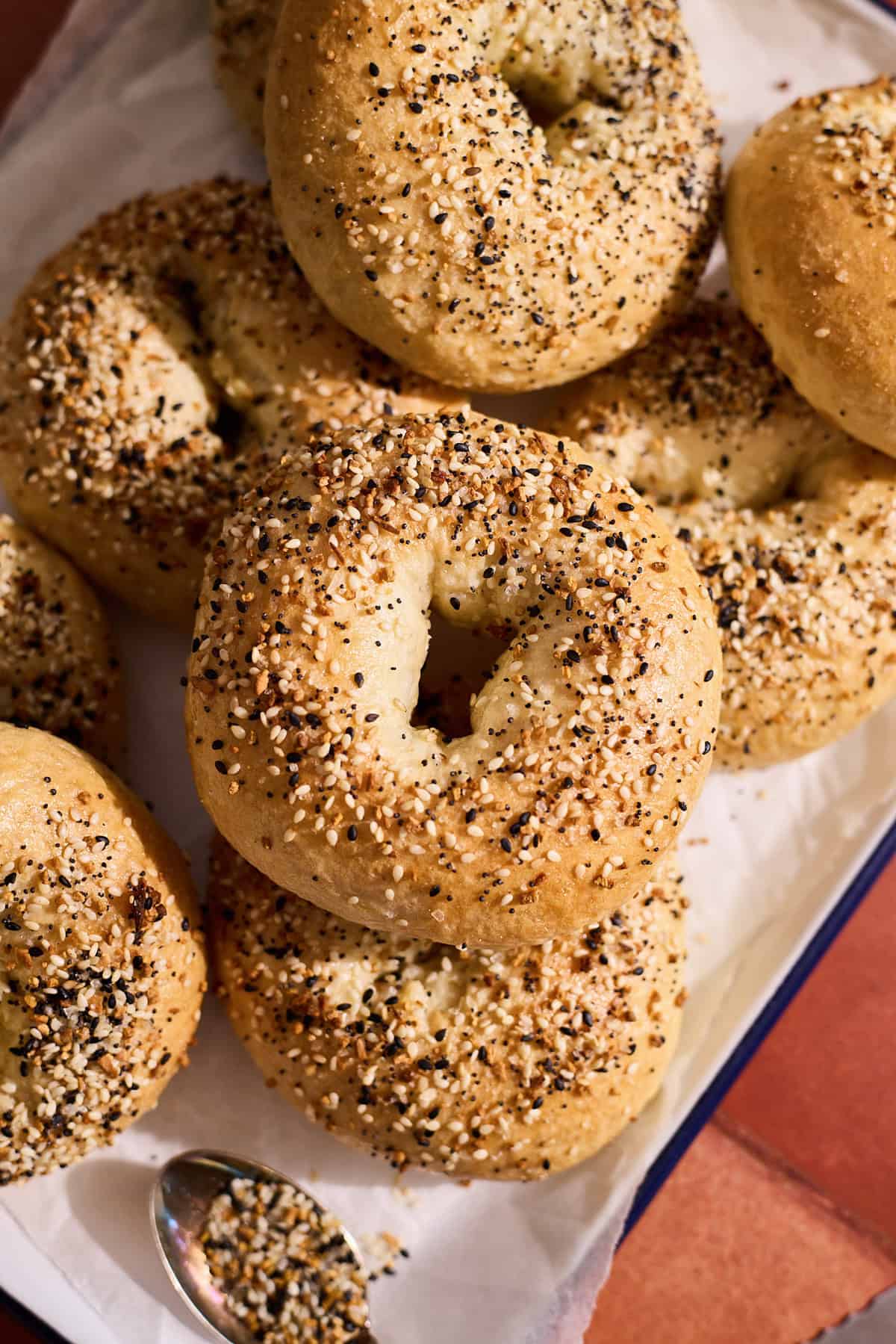A stack of Homemade Everything Bagels on a white tray.