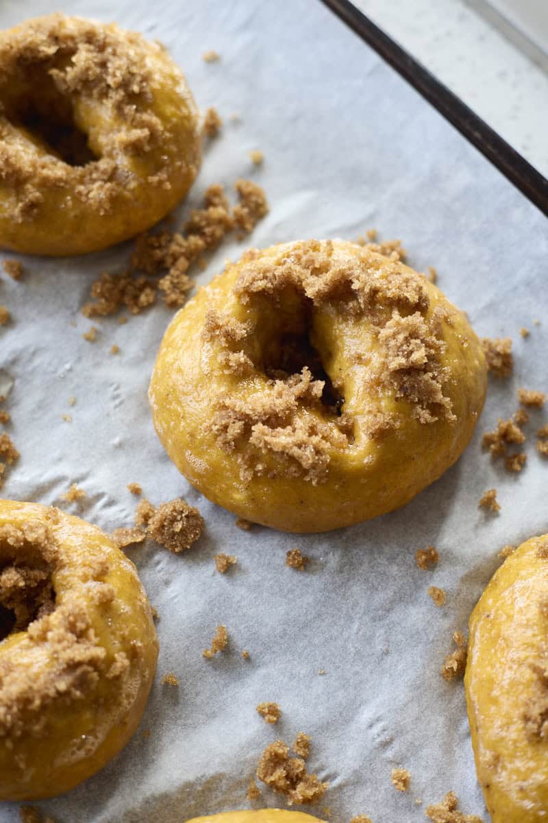 Bagels sprinkled with cinnamon sugar topping before baking.