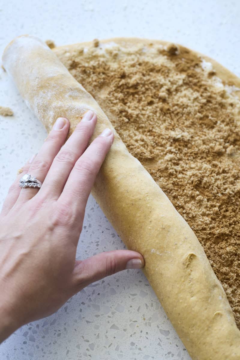 A hand rolling the dough into a long log.