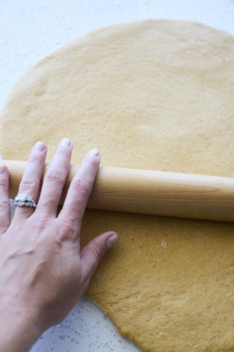 A hand rolling the dough with a rolling pin.