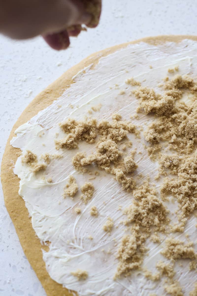 A hand sprinkling the dough with brown sugar.
