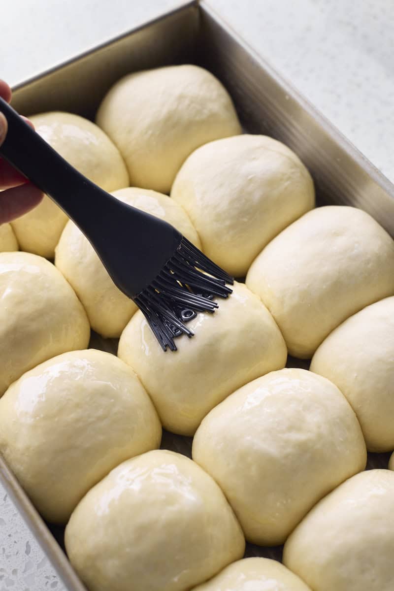 Rolls being brushed with melted butter.