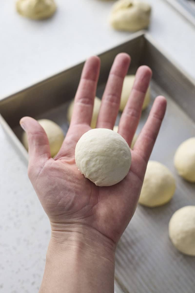 Dough shaped into a roll in the palm of a hand.