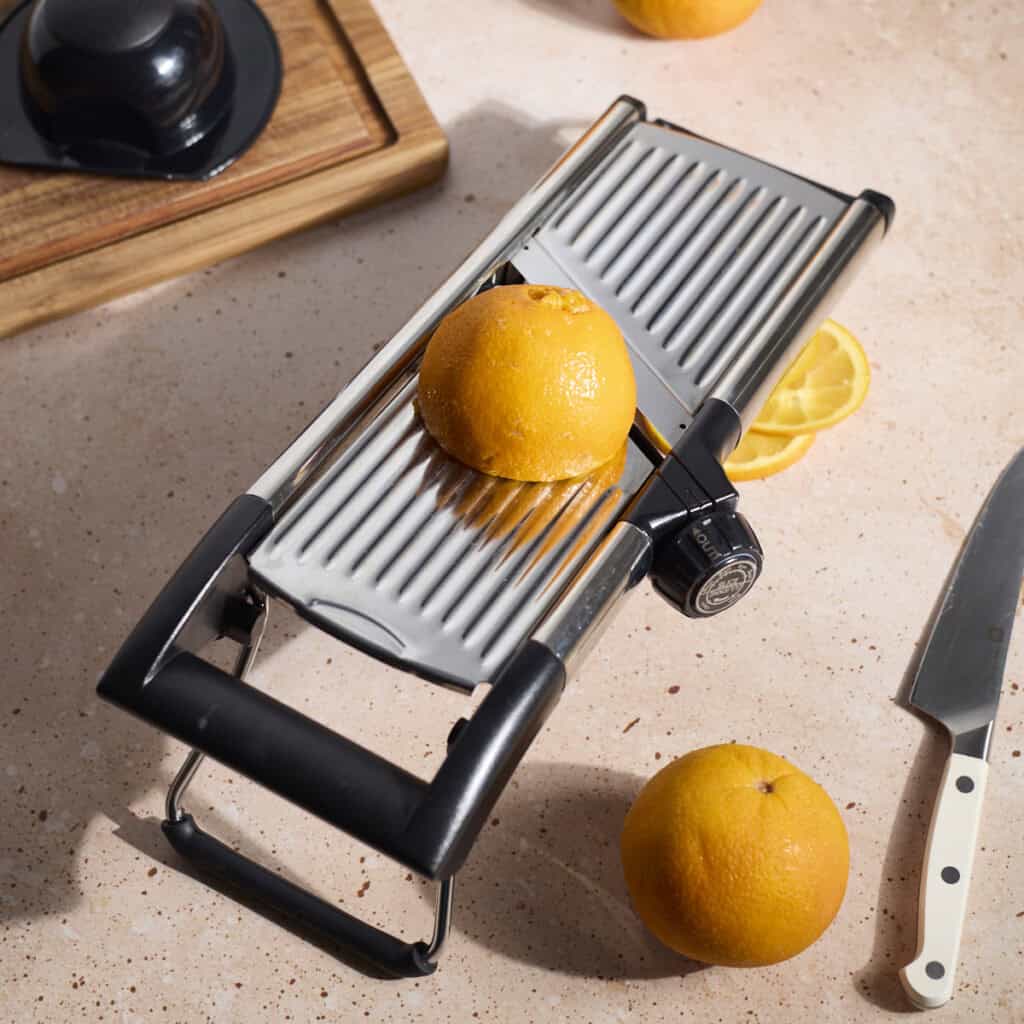 A mandoline slicer with an orange on top.