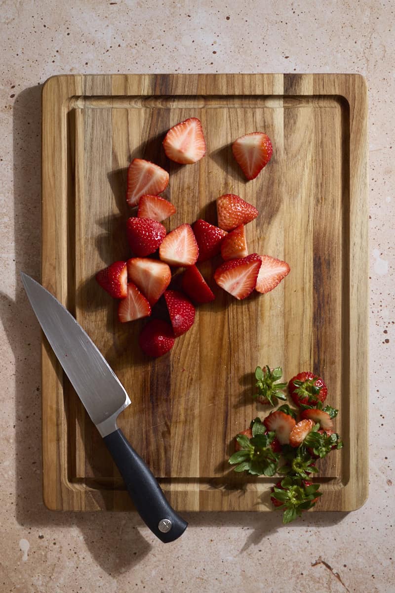 Berries sliced on a wooden cutting board.
