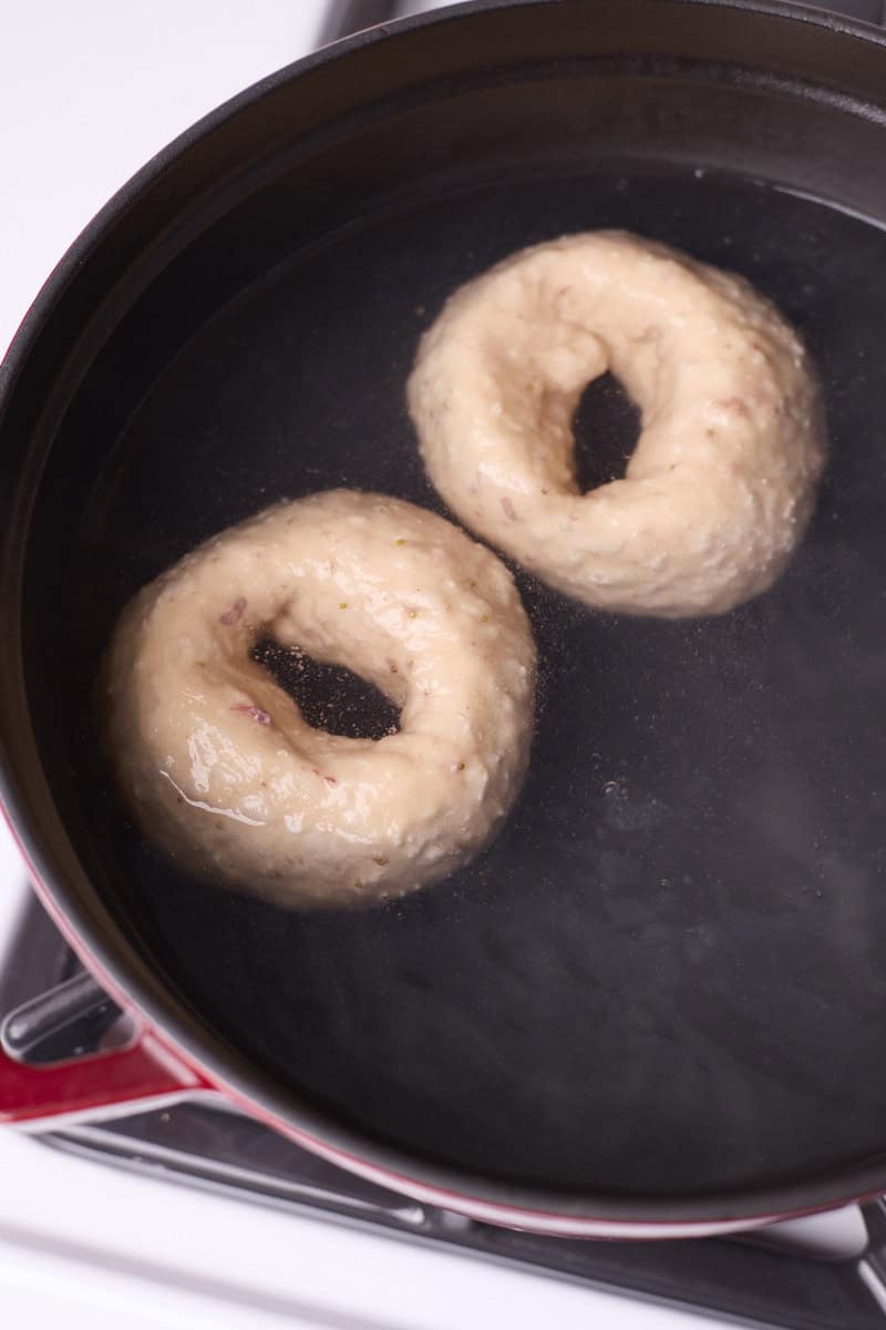 Bagels boiling in a pot of water.