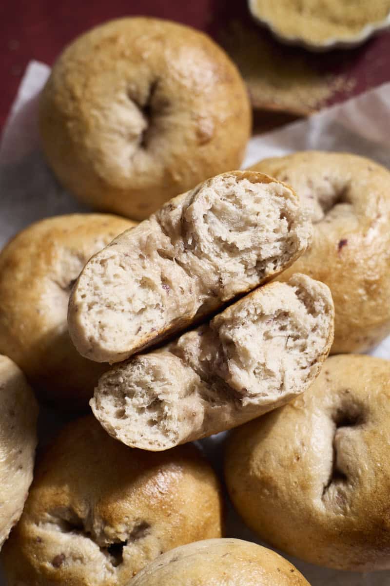 A halved bagel on top of a pile of bagels.