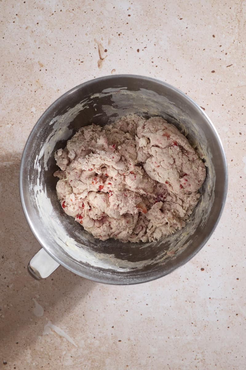 Shaggy dough in the bowl of a stand mixer.