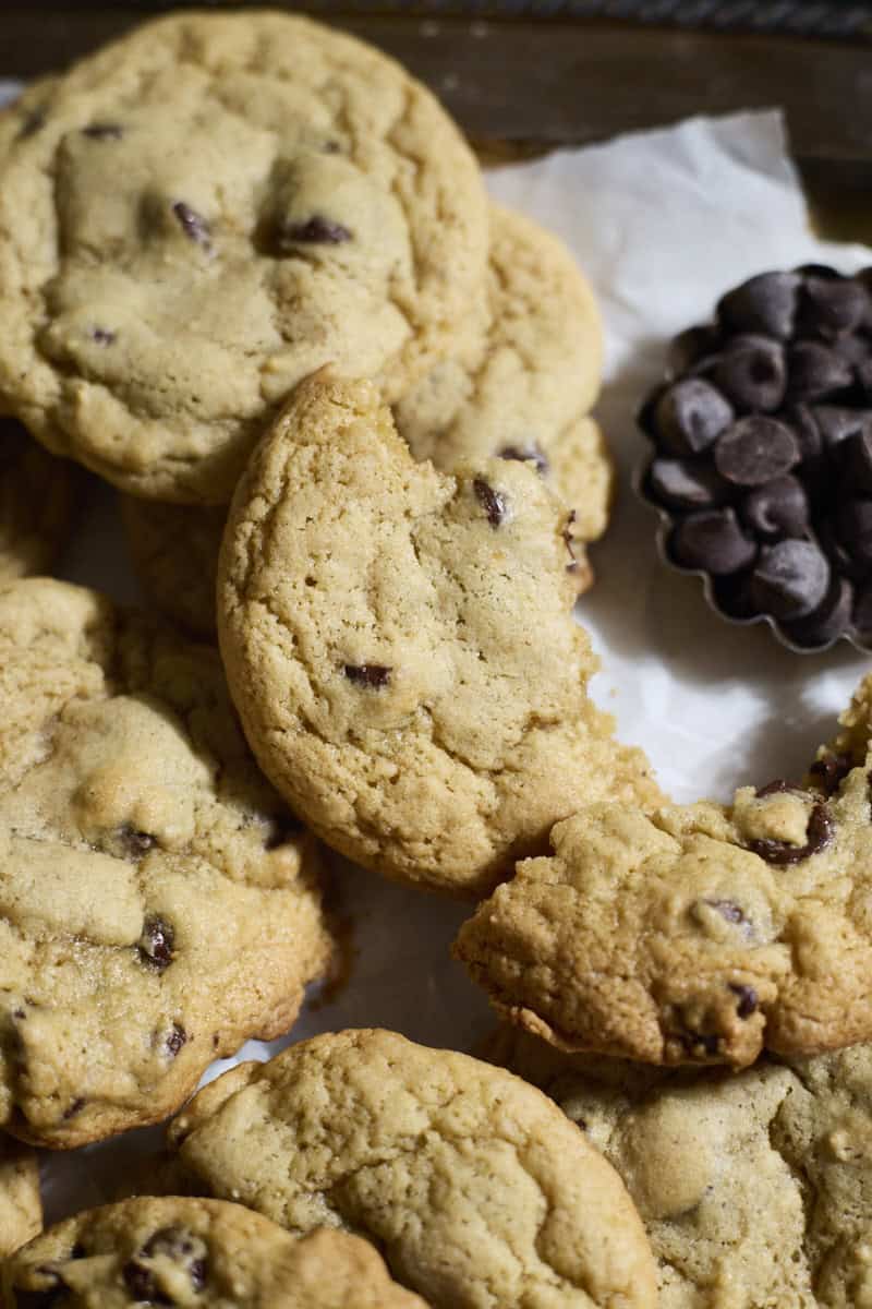 A cookie half on top of a pile of cookies.