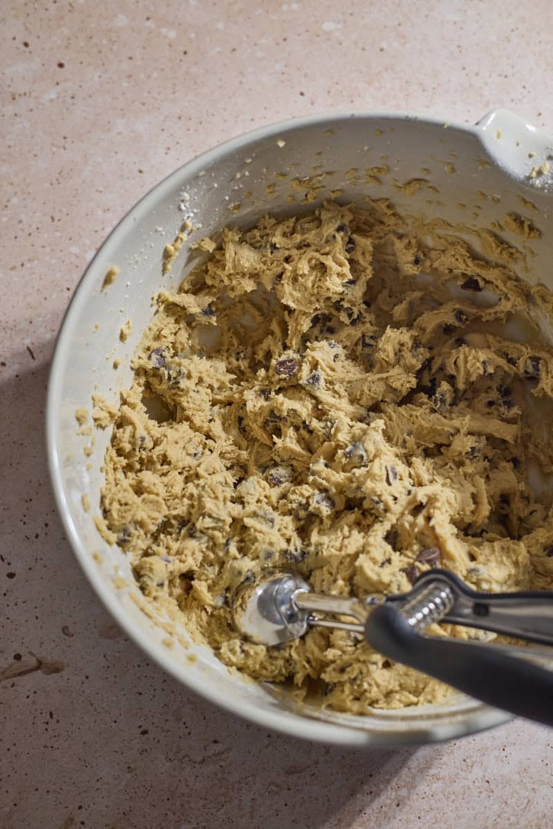 Cookie dough in a bowl with a cookie scoop.