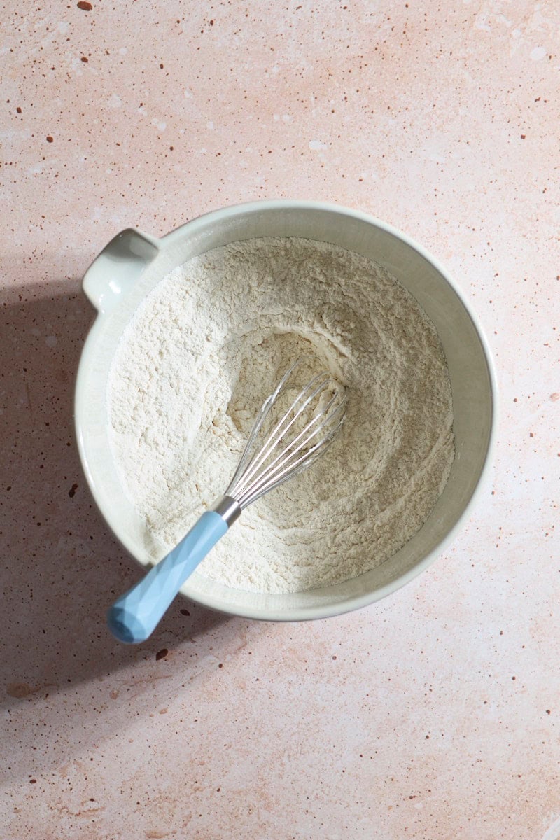 Dry ingredients mixed together in a white bowl with a whisk.