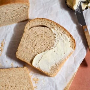 Sourdough Discard Whole Wheat Sandwich Bread slice spread with butter.