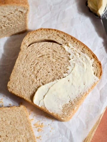 Sourdough Discard Whole Wheat Sandwich Bread slice spread with butter.