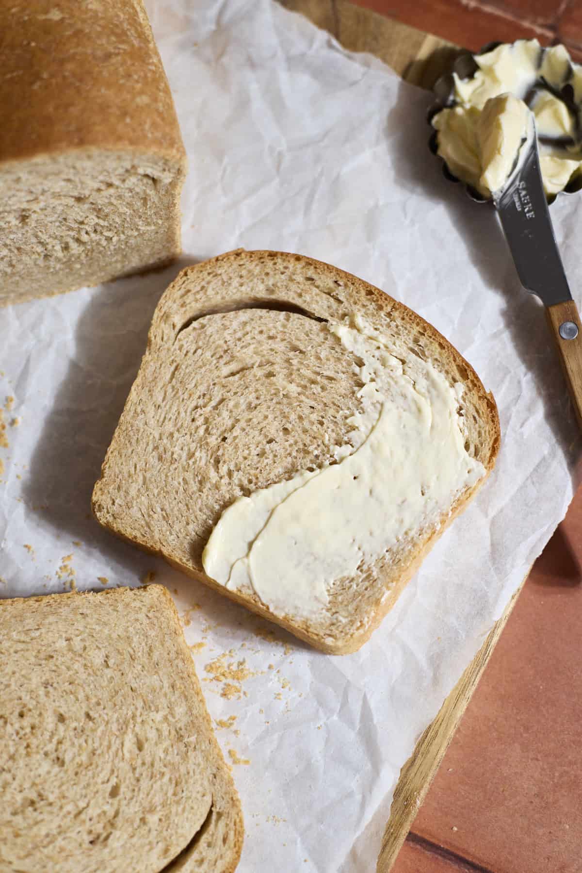 A slice of Sourdough Discard Whole Wheat Sandwich bread with a smear of butter.