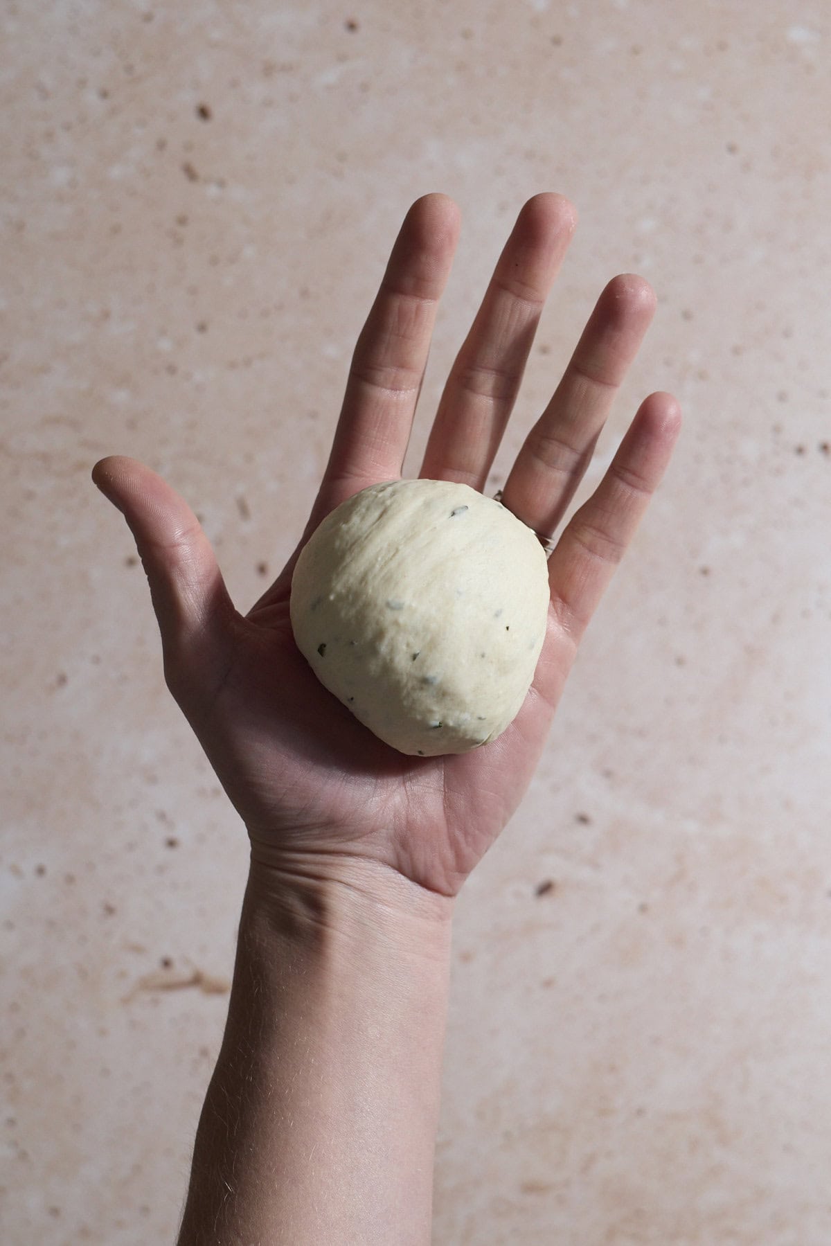 A ball of dough in the palm of a hand.