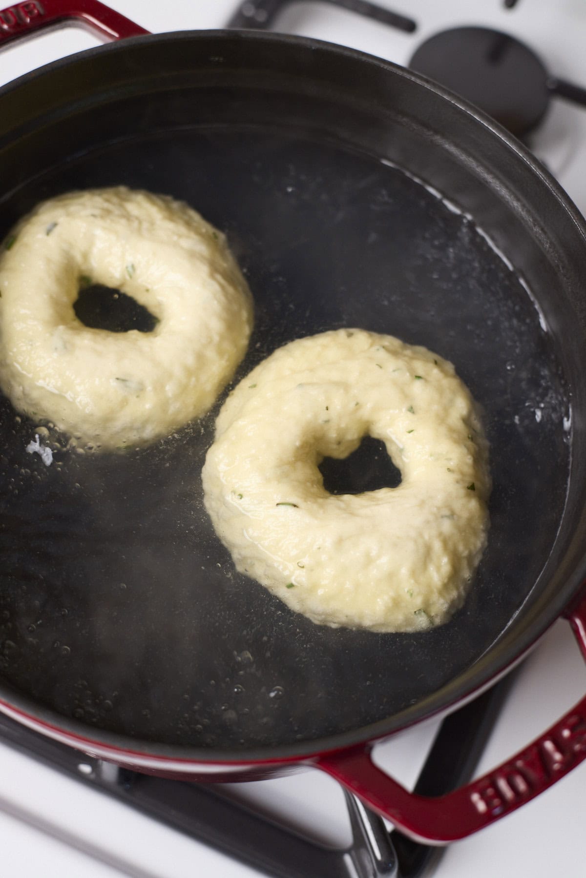 Bagels boiling in a pot of water.