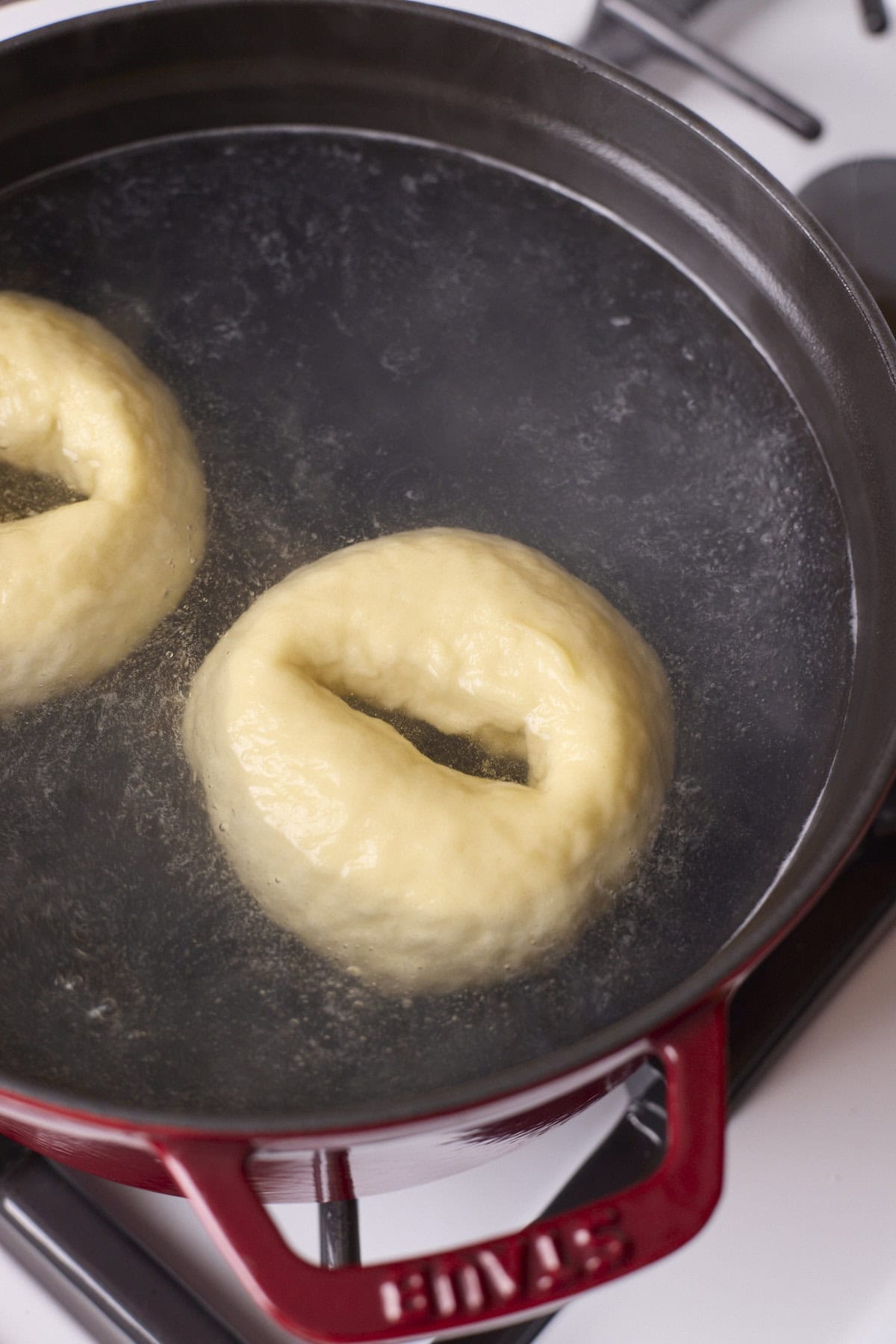Bagels floating in a pot of boiling water.