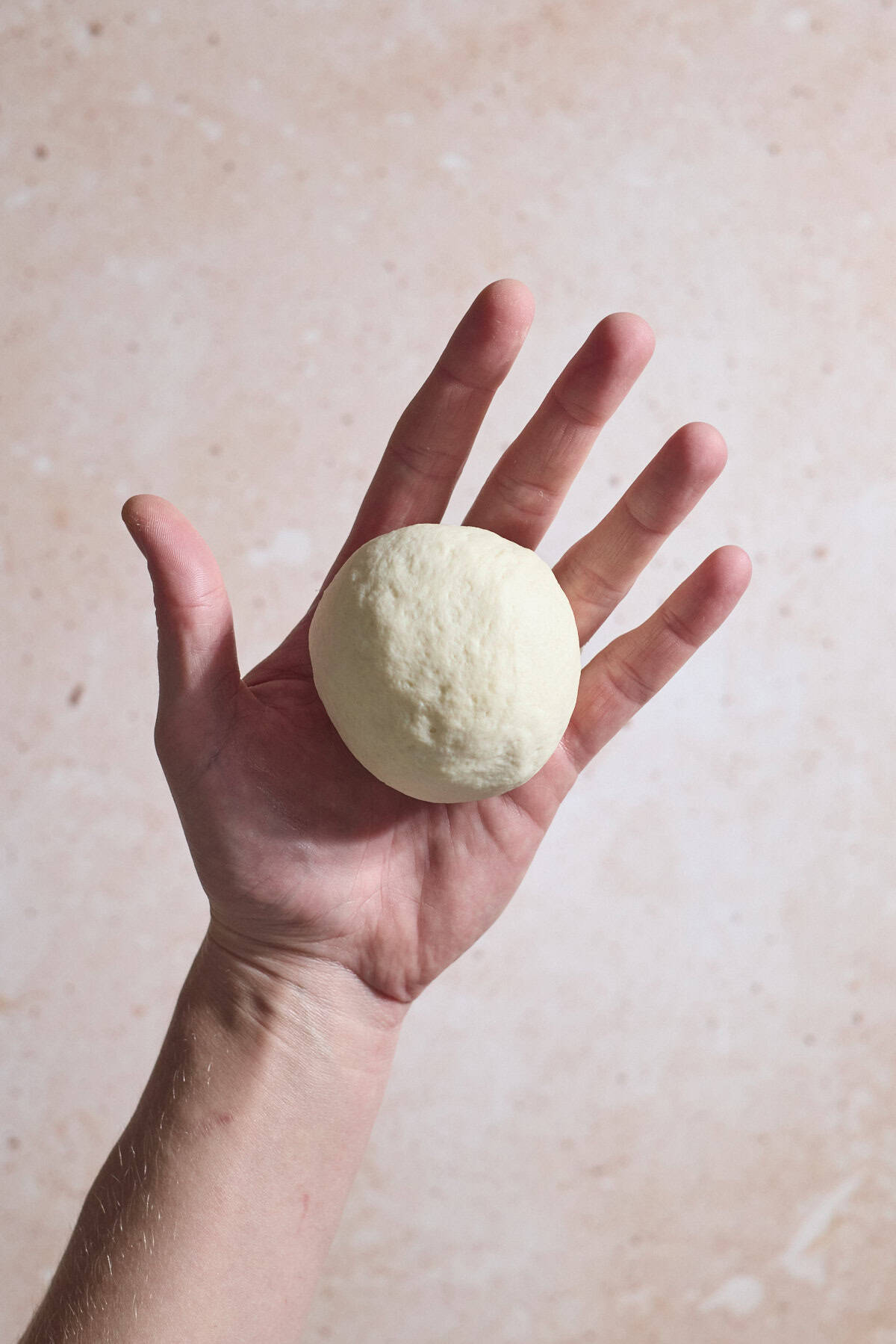 Dough shaped into a ball in the palm of a hand.