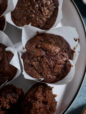 Chocolate Sourdough Zucchini Muffins on a white platter.