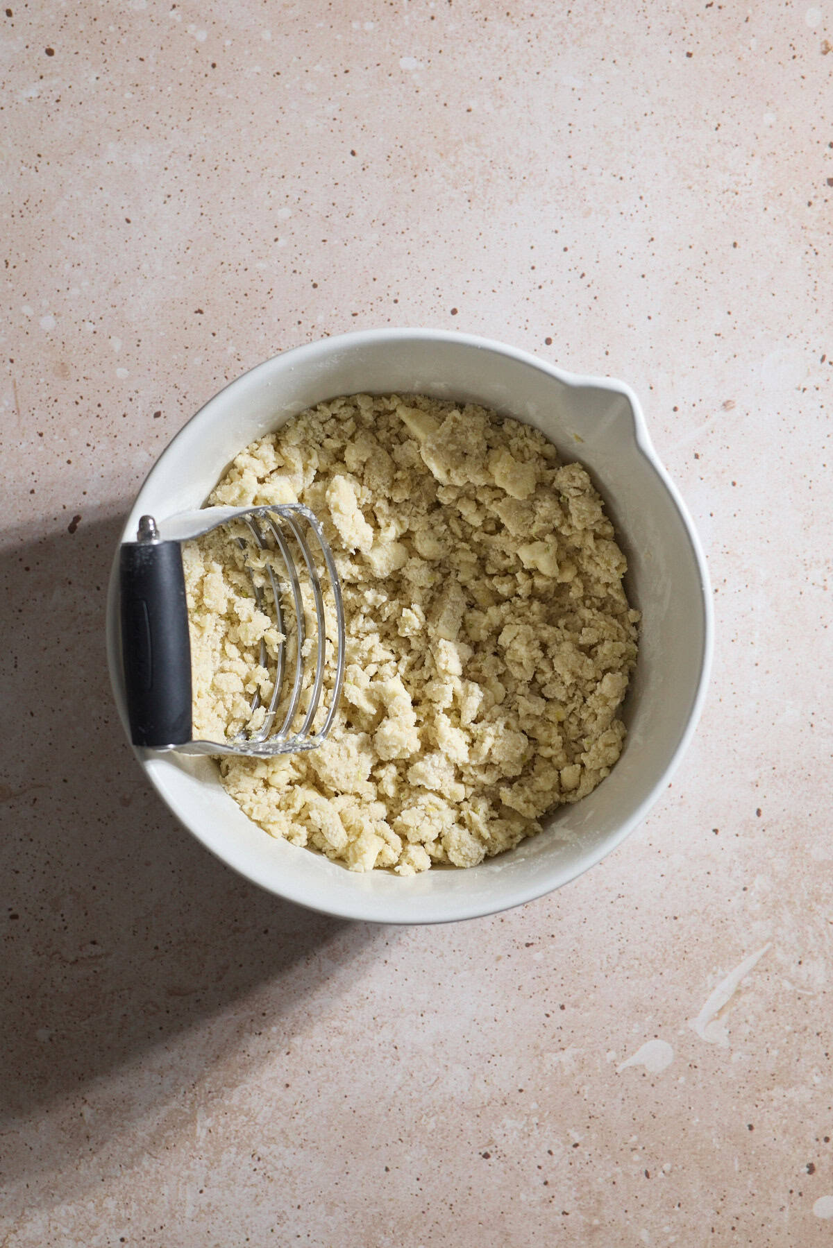 Dough in a bowl with a pastry cutter.