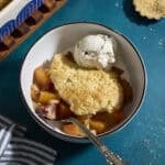Sourdough Peach Cobbler in a bowl with a scoop of vanilla ice cream.