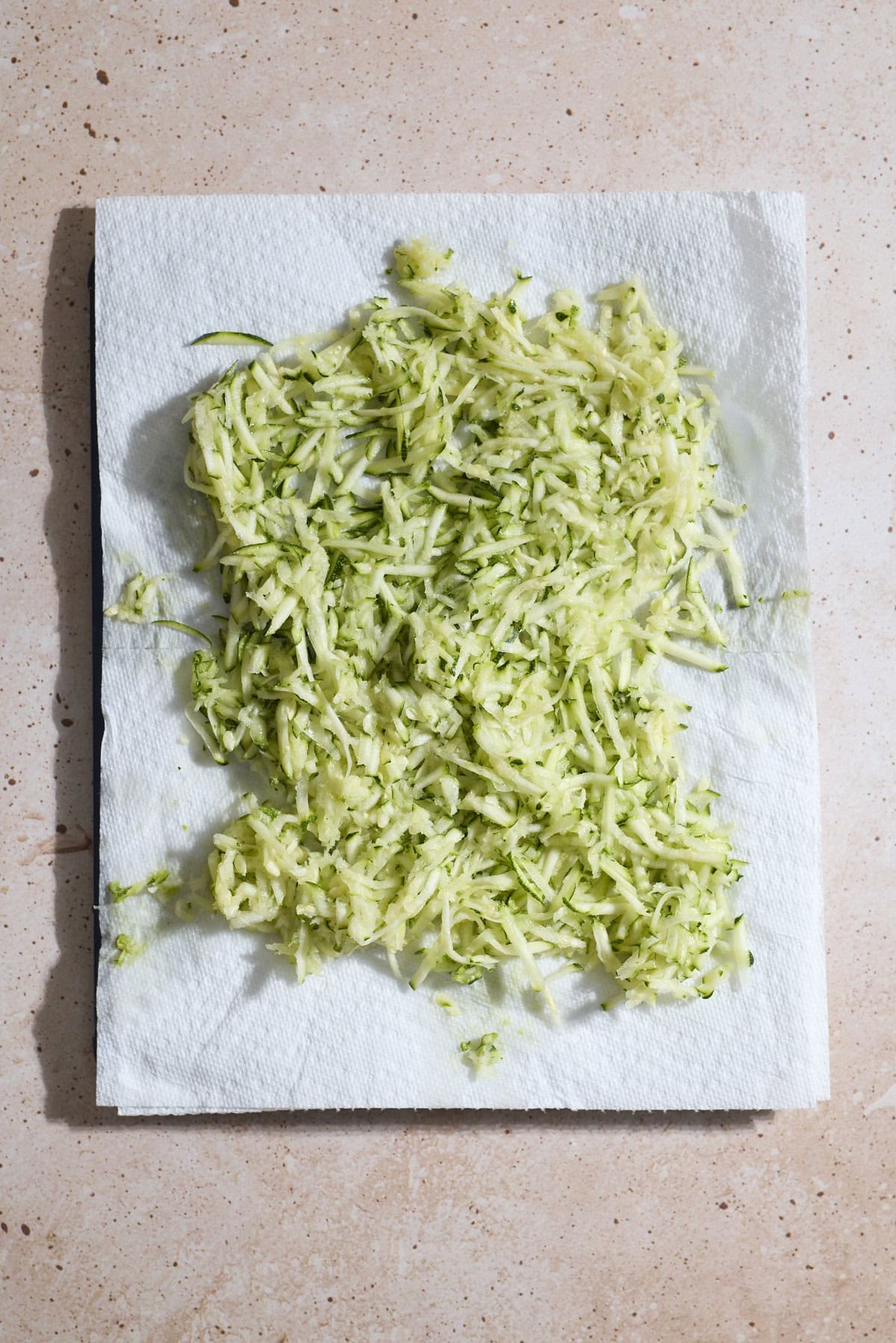 Shredded zucchini on a layer of paper towels.