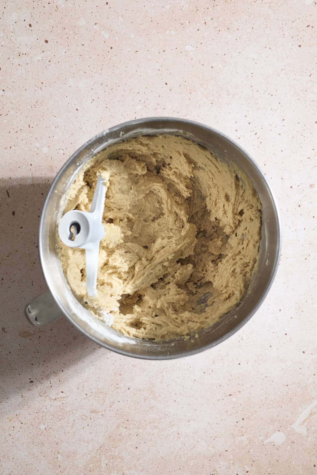 Cookie dough in a bowl of a stand mixer.