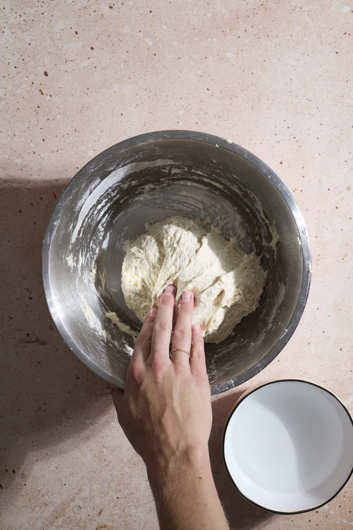 A hand folding the dough over on itself.