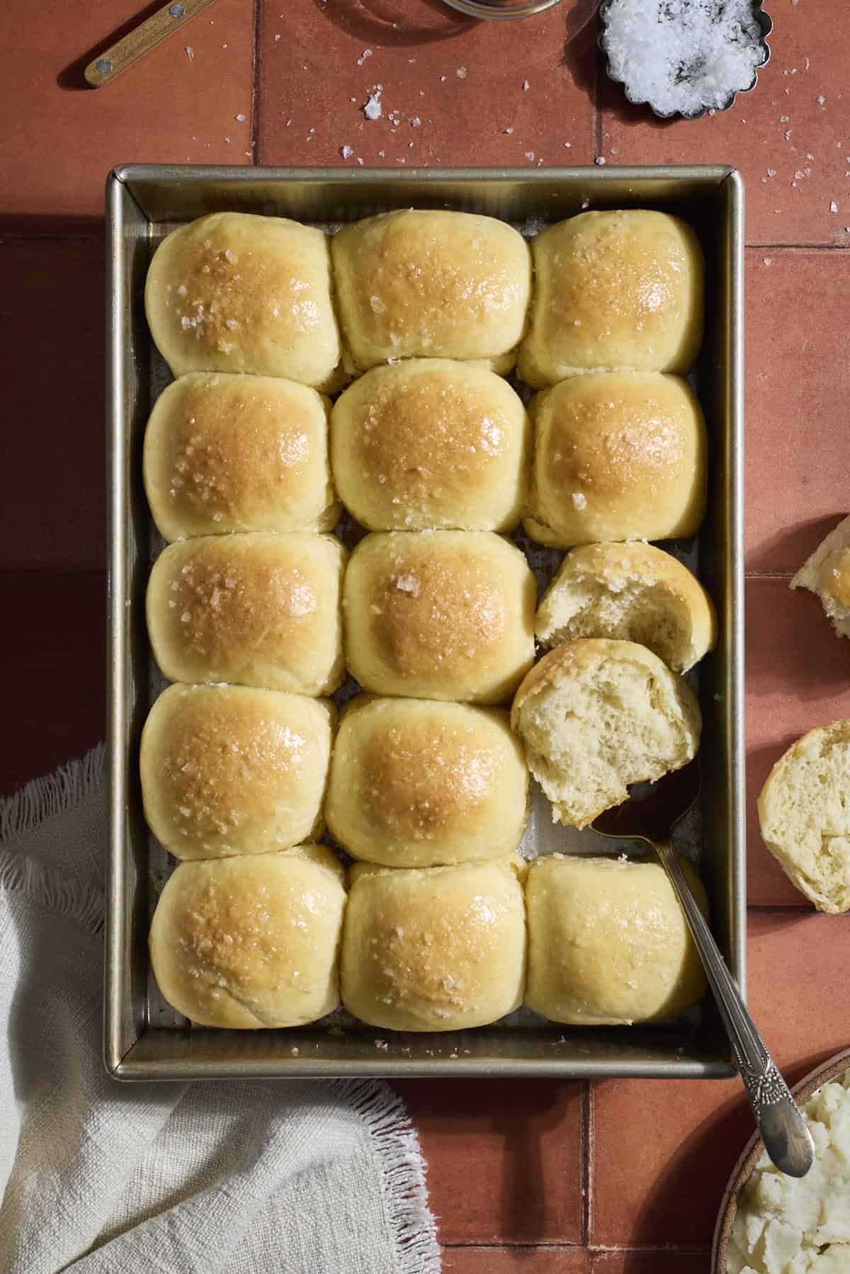 Sourdough Discard Potato Dinner Rolls topped with melted butter and flaky sea salt.