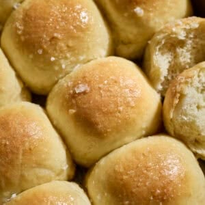 Sourdough Discard Potato Dinner Rolls topped with melted butter and flaky sea salt.